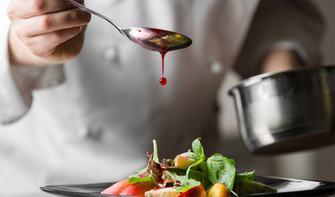 plan rapproché sur un chef cuisinier en train de finaliser la préparation d'une assiette